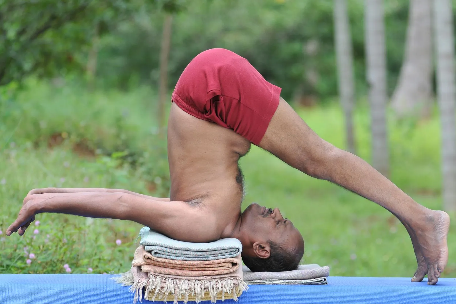 Narayan Sir in a supported shoulder-stand variation on folded blankets, outdoors